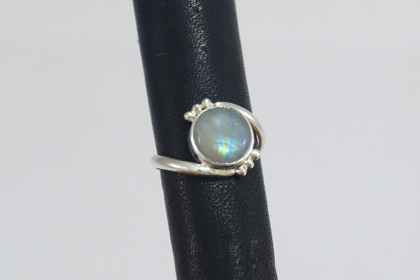Round natural rainbow moonstone set in sterling silver bezel on a bypass ring band with silver bubble accents.