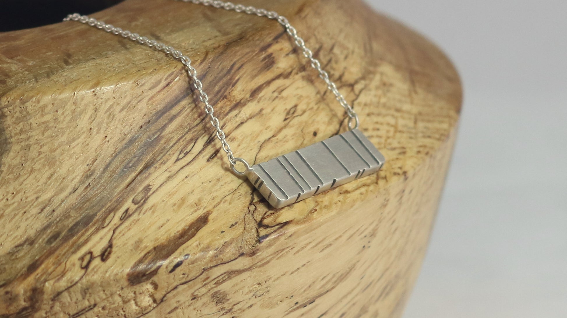 A large sterling silver bar with randomly spaced black lines.