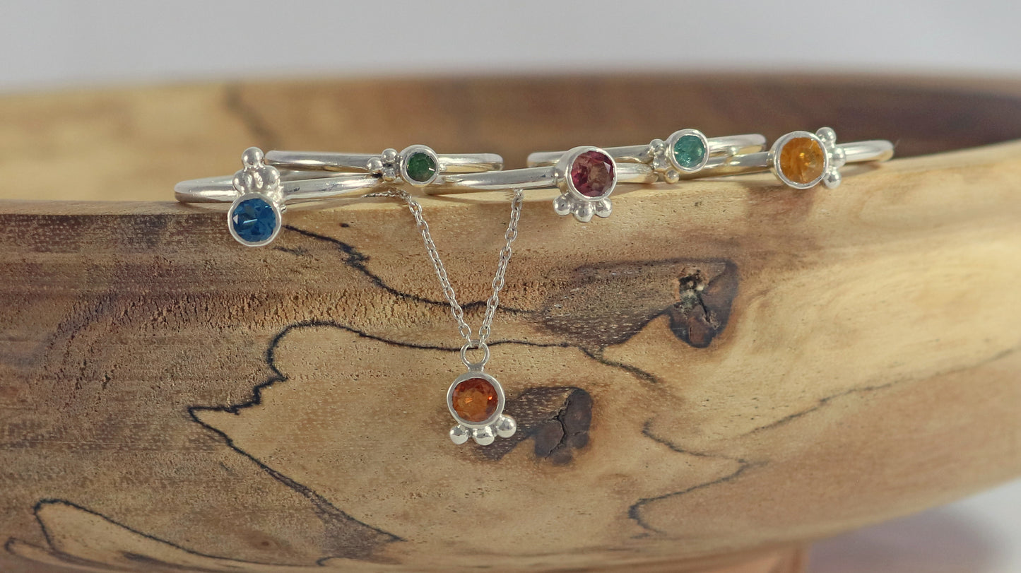 Natural gemstone set in sterling silver bezel on a sterling silver ring band with 3 silver bubbles in a pyramid.