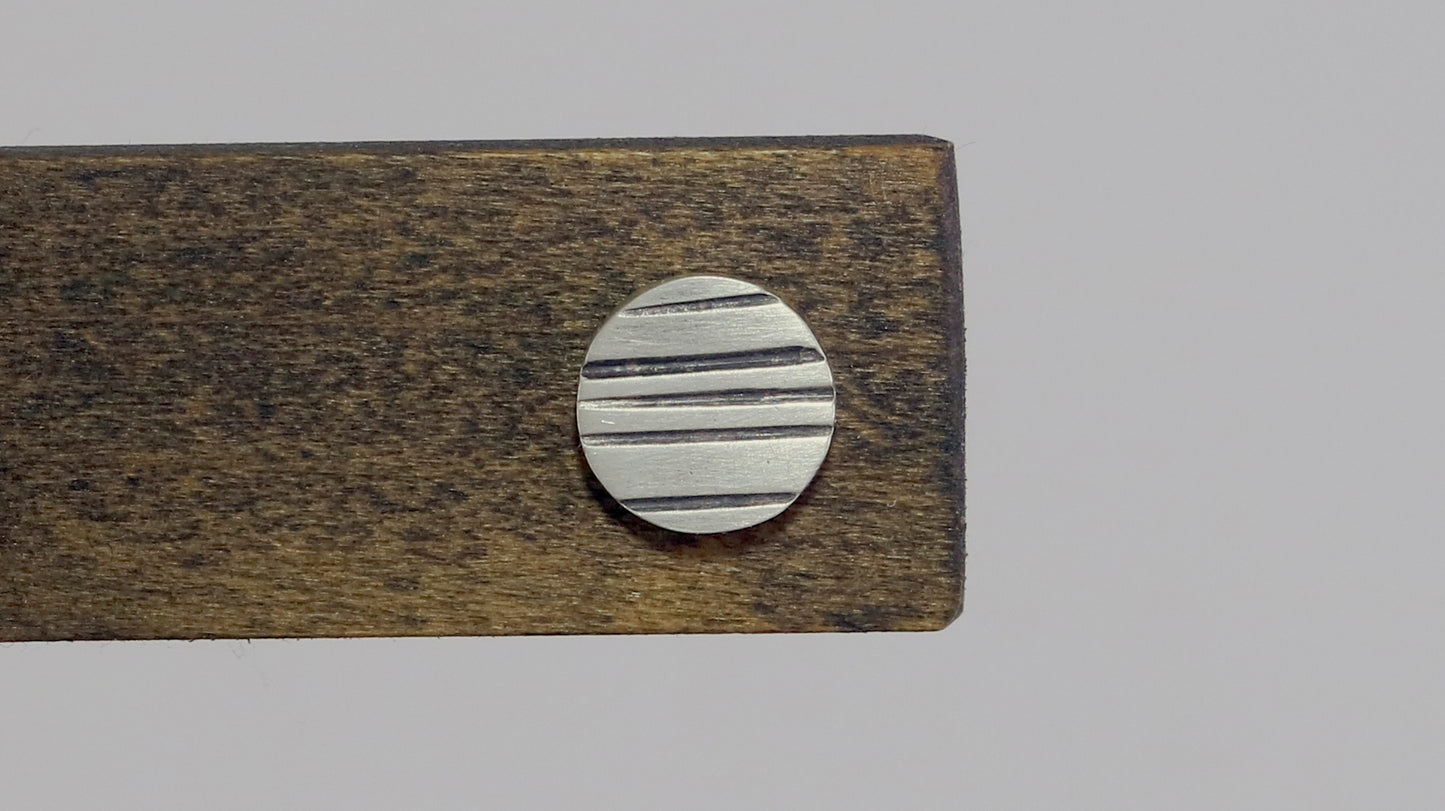 Round silver disc studs with black lines randomly spaced.