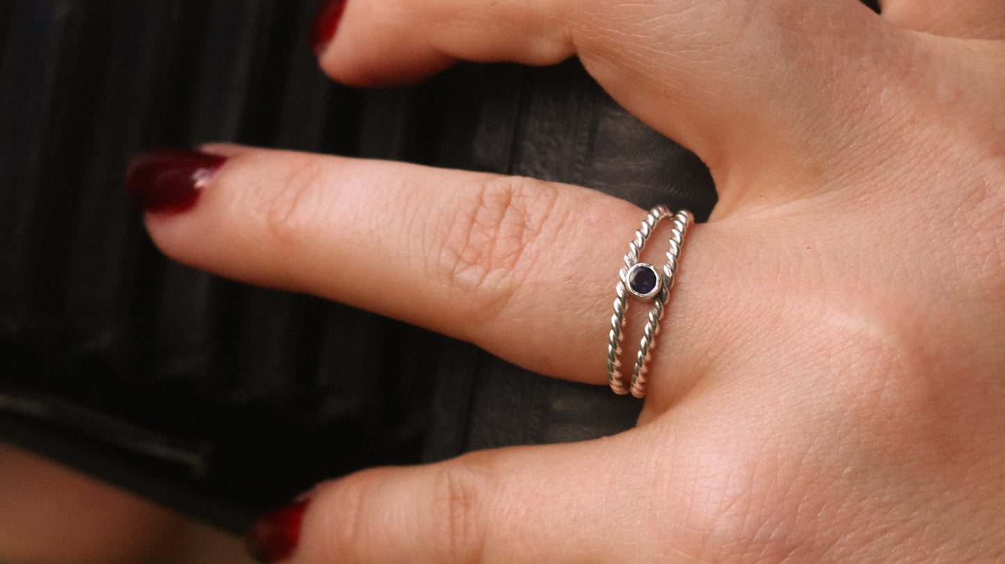 Round natural gemstone set in a sterling silver bezel between two twisted silver ring bands.