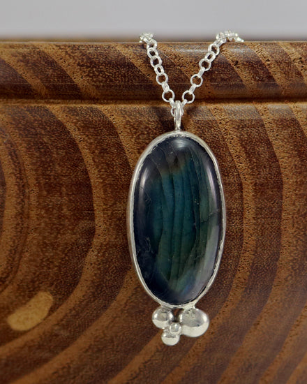 Oval natural Labradorite gemstone set in sterling silver bezel with 4 bubble cluster accent on a sterling silver chain.