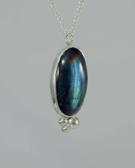 Oval natural Labradorite gemstone set in sterling silver bezel with 4 bubble cluster accent on a sterling silver chain.