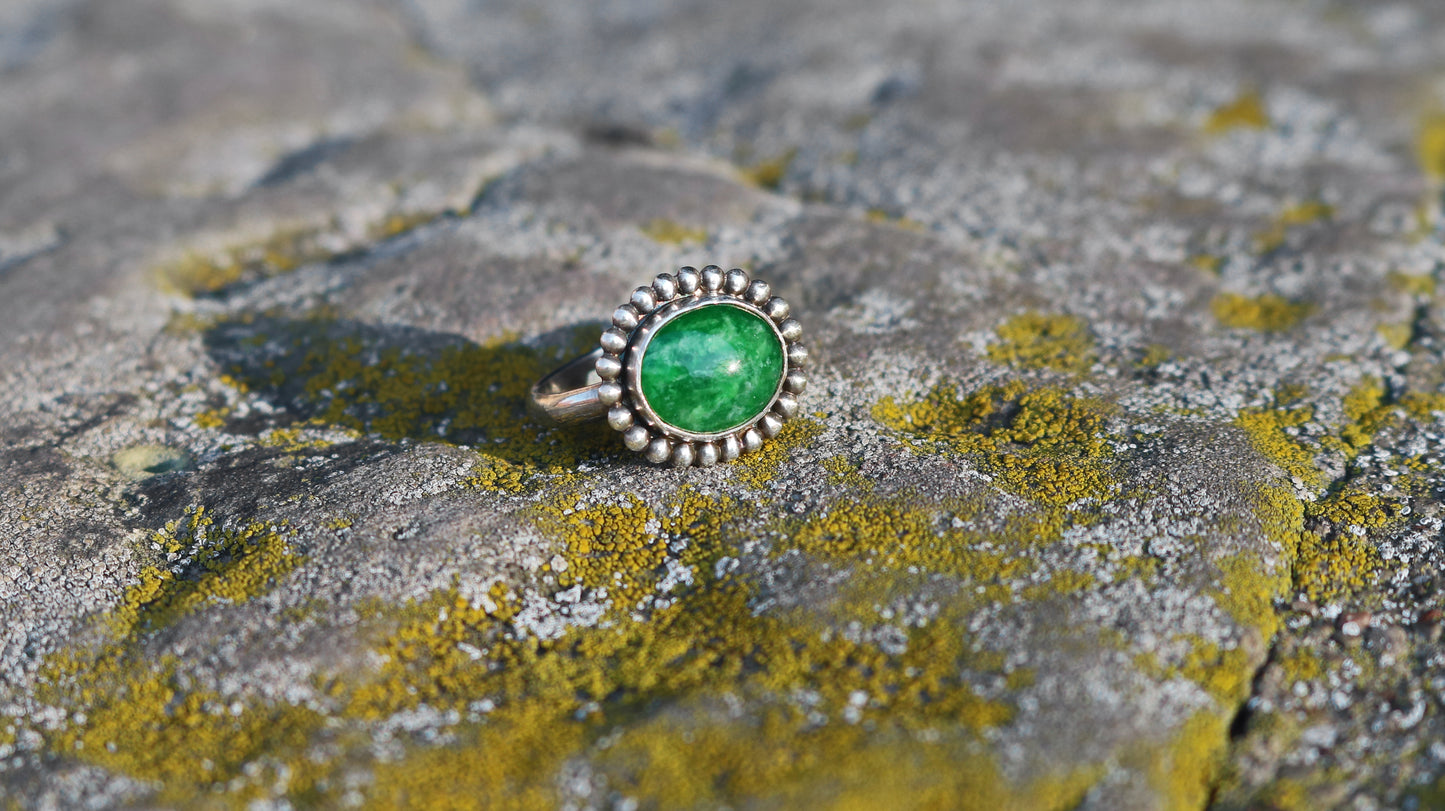 Horizontal oval natural gemstone set in sterling silver bezel with halo of silver bubbles.