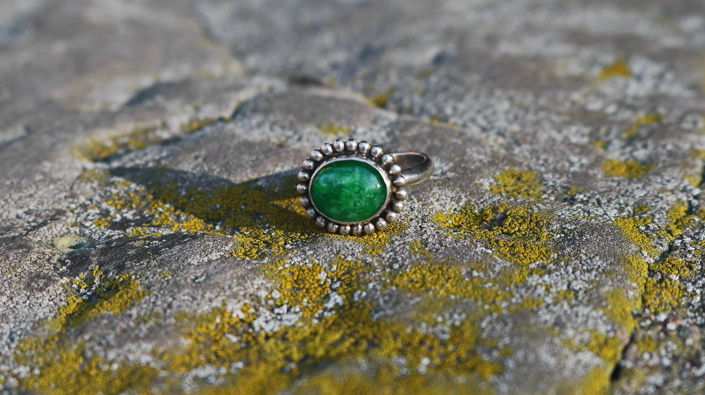 Horizontal oval natural gemstone set in sterling silver bezel with halo of silver bubbles..