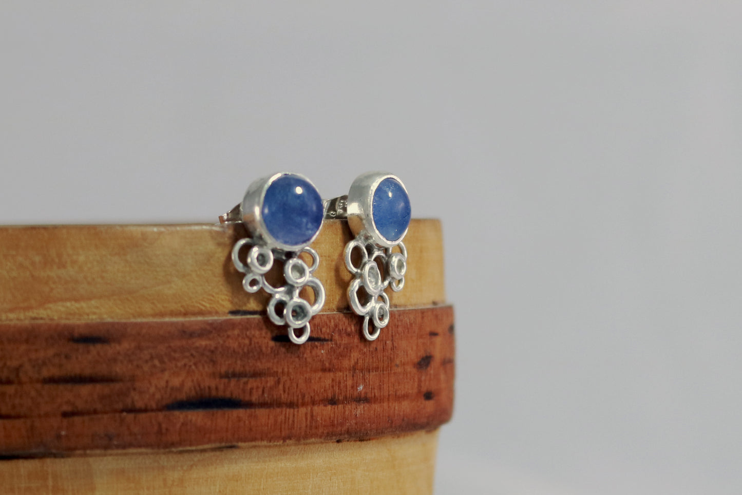 7mm round tanzanite gems set in sterling silver bezels with silver circle clusters at the bottom.