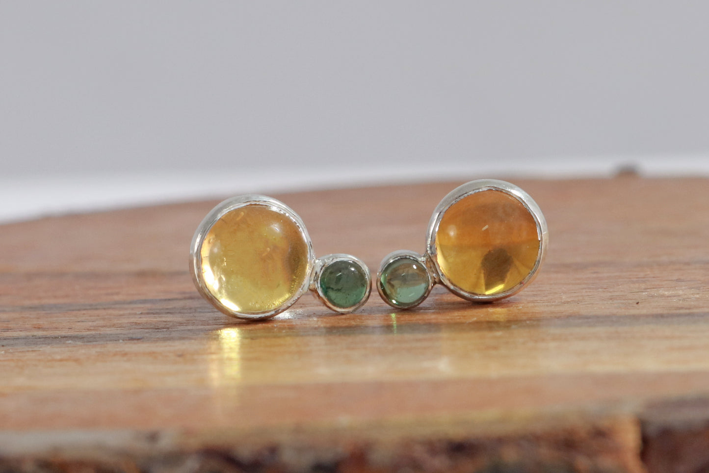 Stud earrings, natural round citrine gemstones set in sterling silver bezels with a small natural green tourmaline bezel set below.