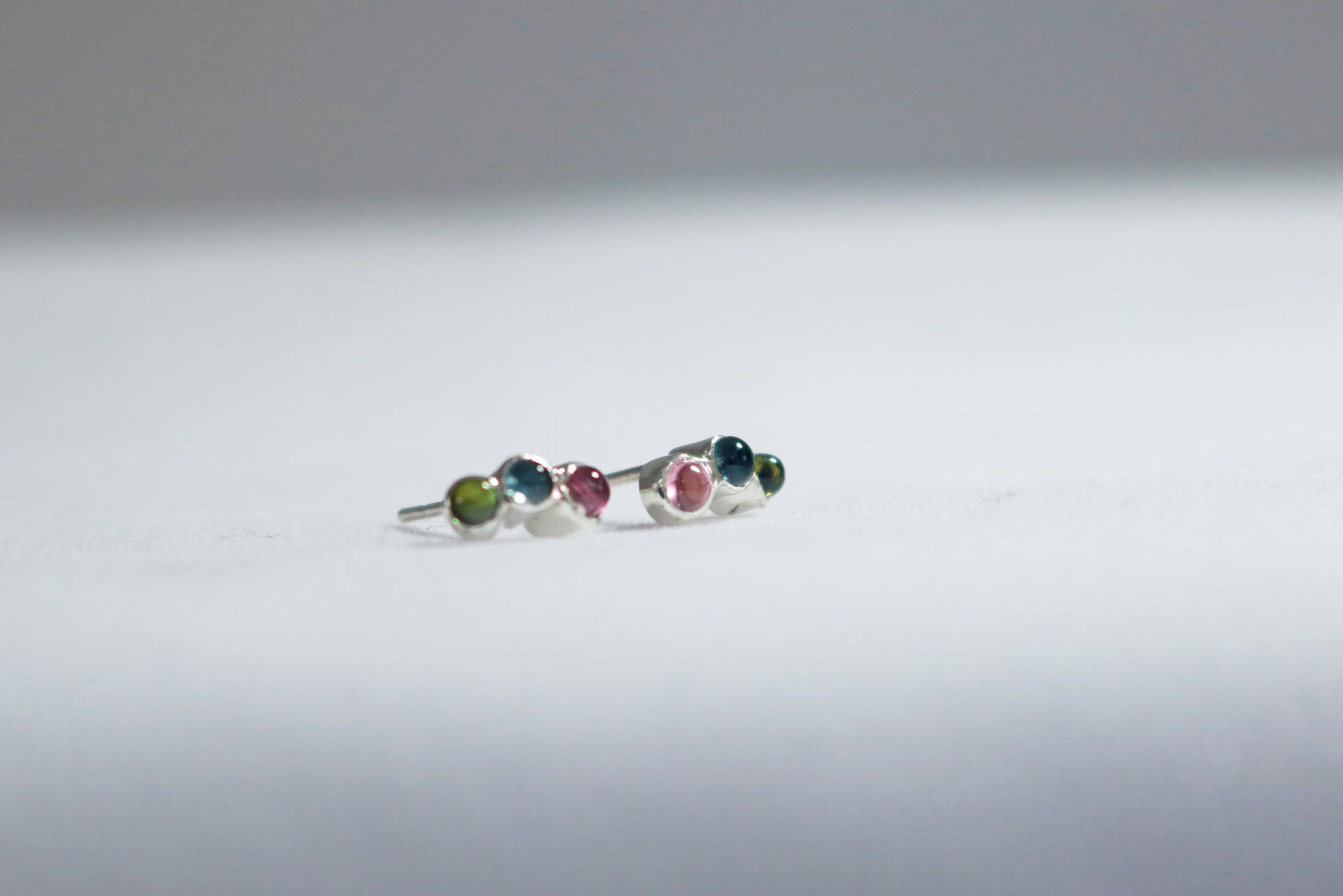Stud earrings, 3 round natural gemstones set in sterling silver bezels on a curve.