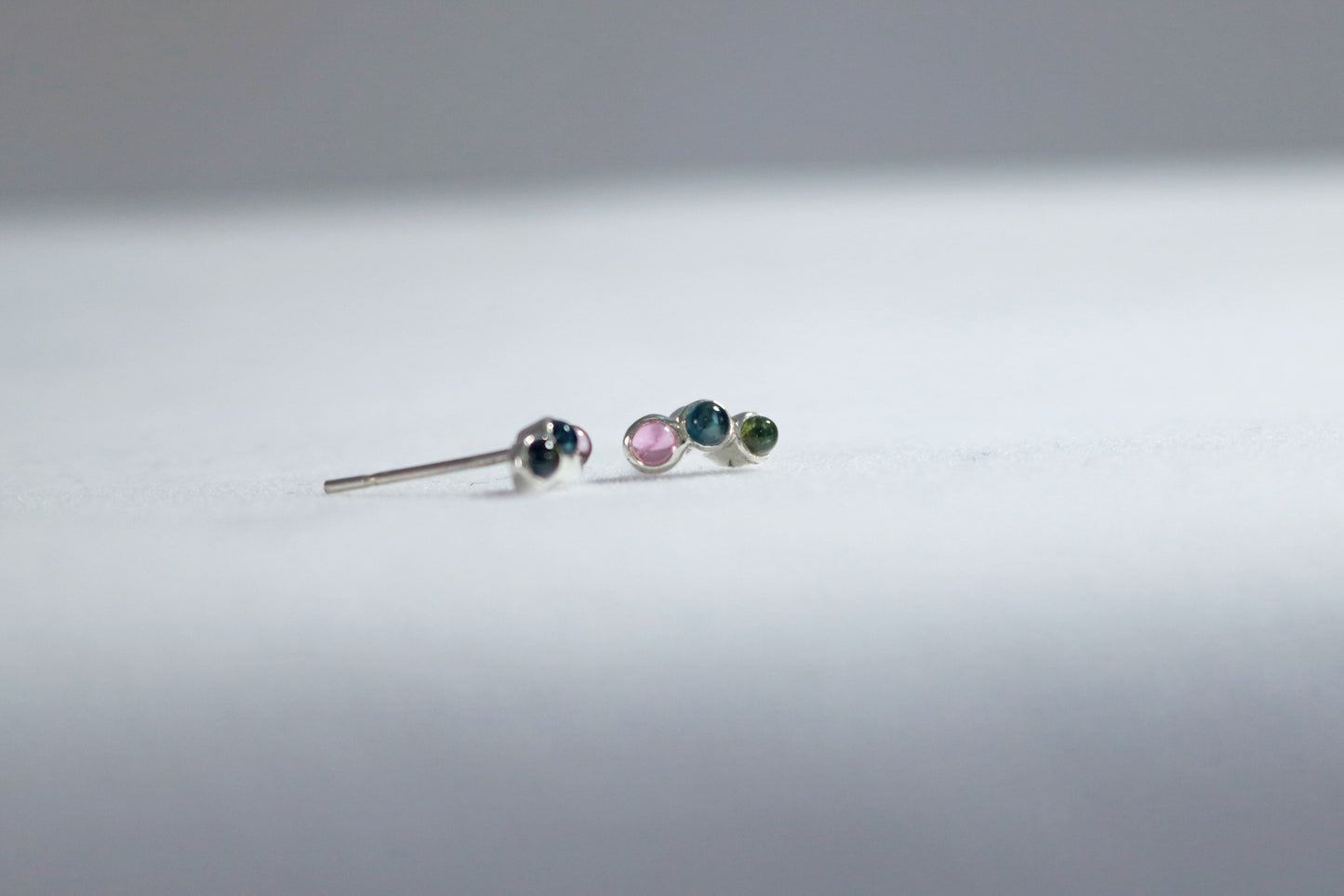 Stud earrings, 3 round natural gemstones set in sterling silver bezels on a curve.