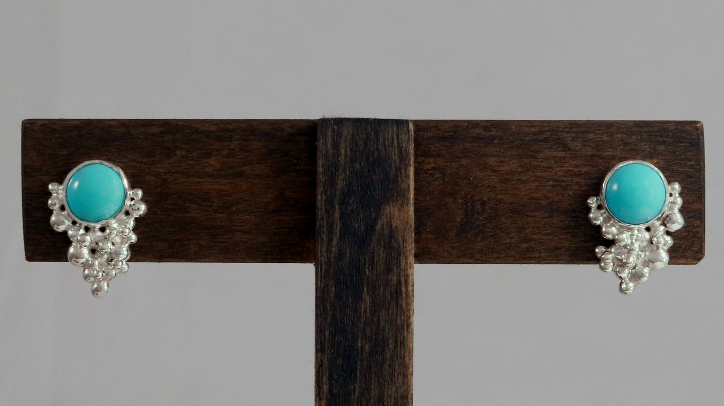 Studs with 8mm round, turquoise stones set in sterling silver with silver climbing bubble tumble clusters going up one side of the stone.