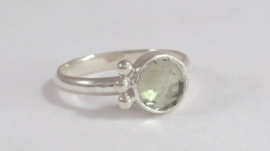 A silver ring with an 8mm round rose cut green amethyst gemstone set in sterling silver. 3 Silver bubble accents aligned along the side.
