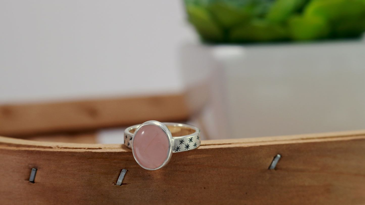 Oval natural gemstone set in sterling silver bezel on a wide sterling silver ring band with checker board of hand cut black stars on either side.
