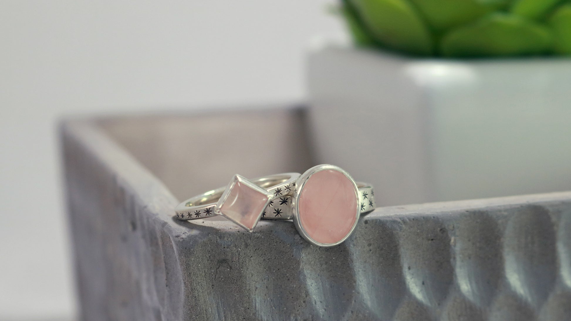 Oval natural gemstone set in sterling silver bezel on a wide sterling silver ring band with checker board of hand cut black stars on either side.