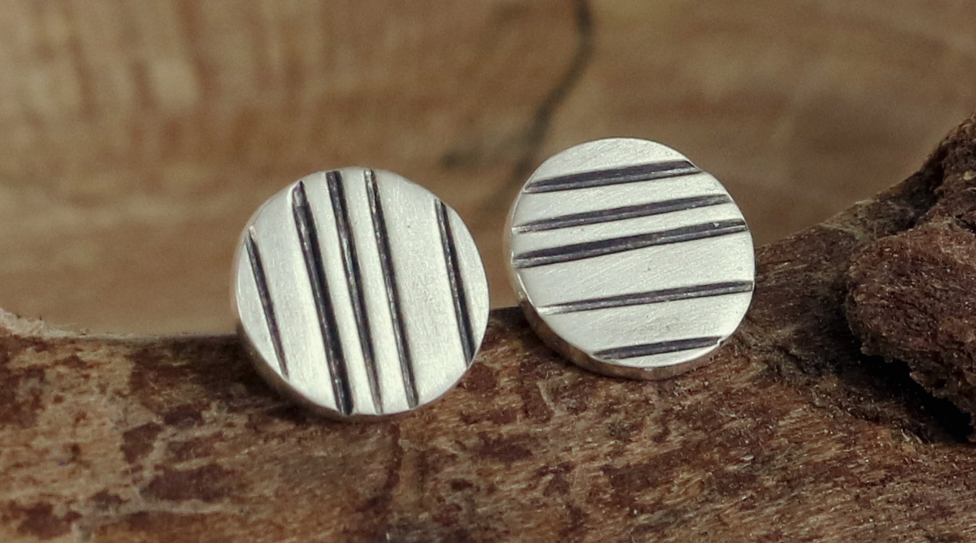 Round silver disc studs with black lines randomly spaced.
