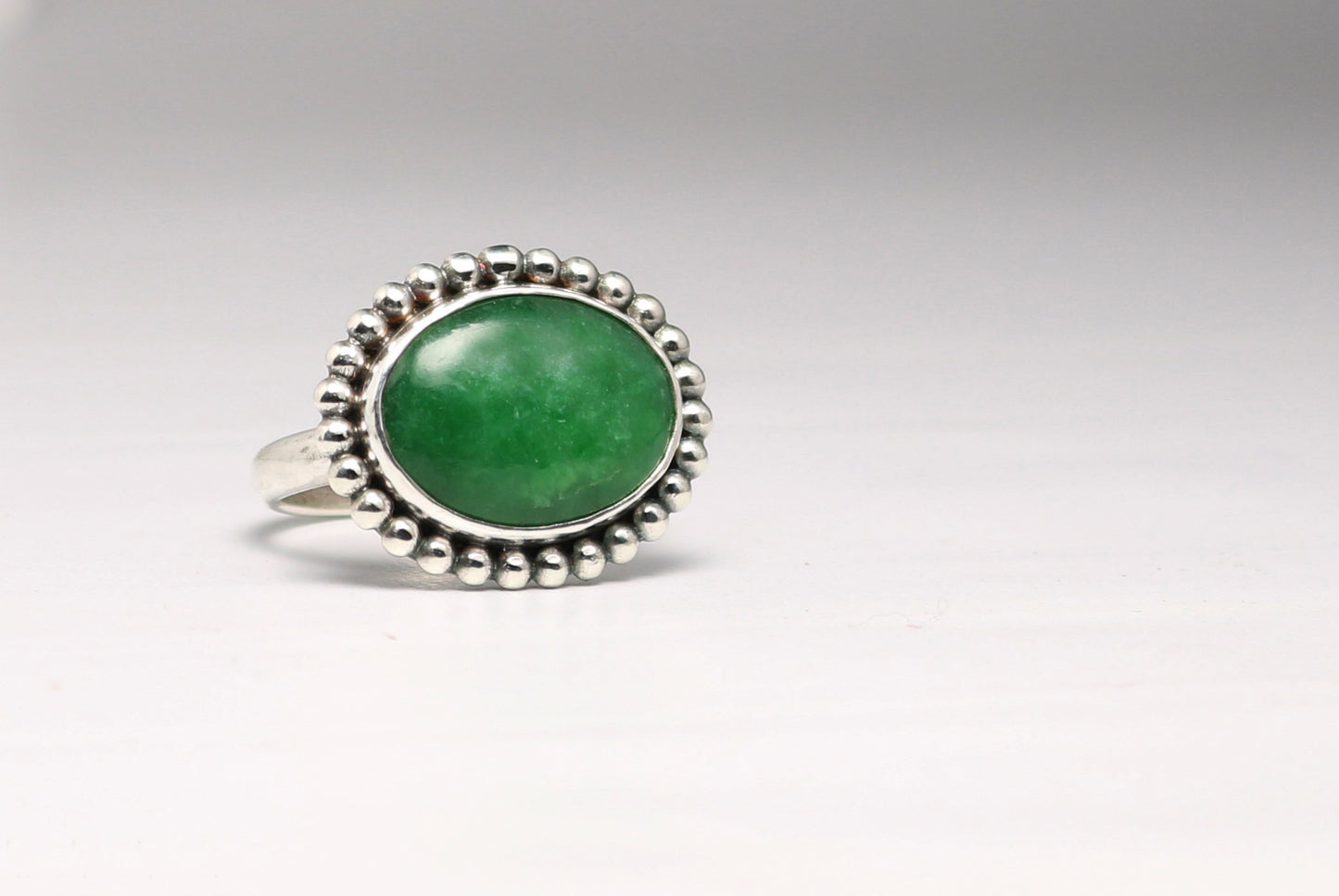 Horizontal oval natural gemstone set in sterling silver bezel with halo of silver bubbles.