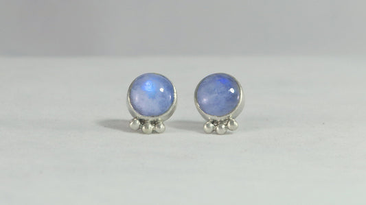 A pair of round rainbow moonstone stud earrings with 3 silver bubbles in a row at the bottom.