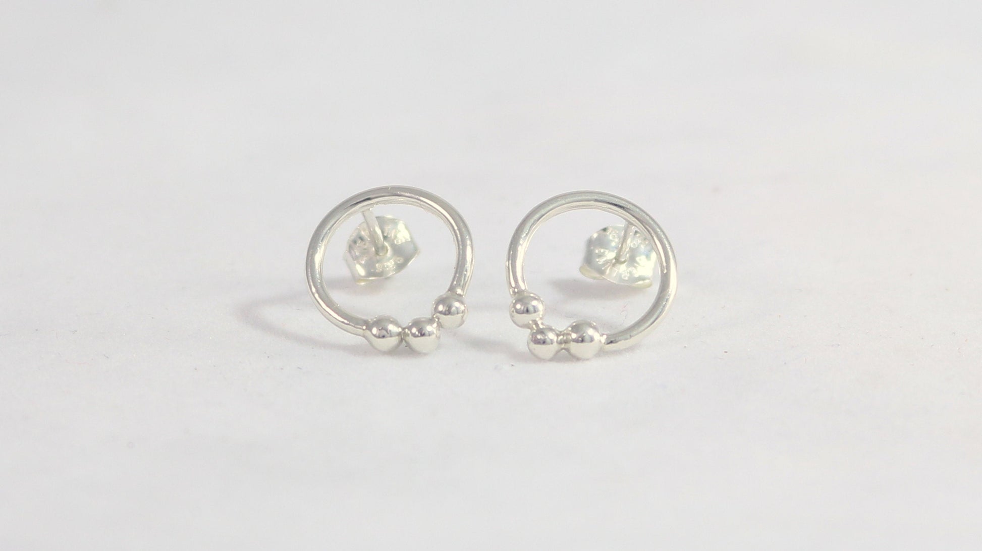 Sterling silver circle stud earrings with three silver bubbles at the bottom.