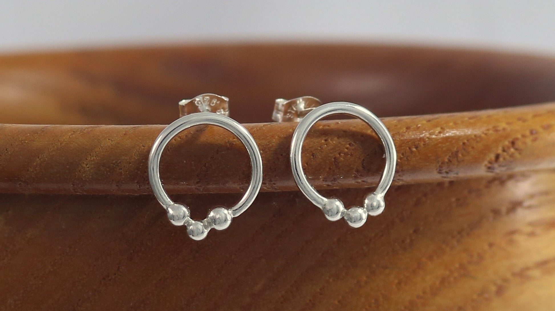 Sterling silver circle stud earrings with three silver bubbles at the bottom.
