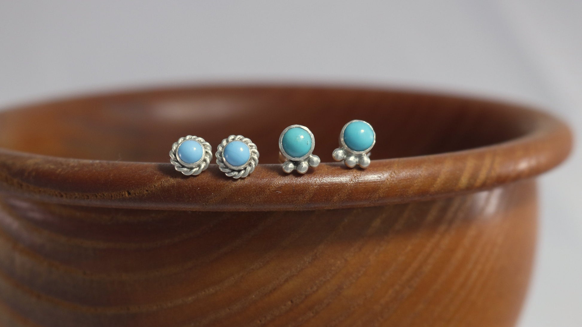 A pair of 5mm, round turquoise stones set in sterling silver with three silver bubbles aligned along the bezel.