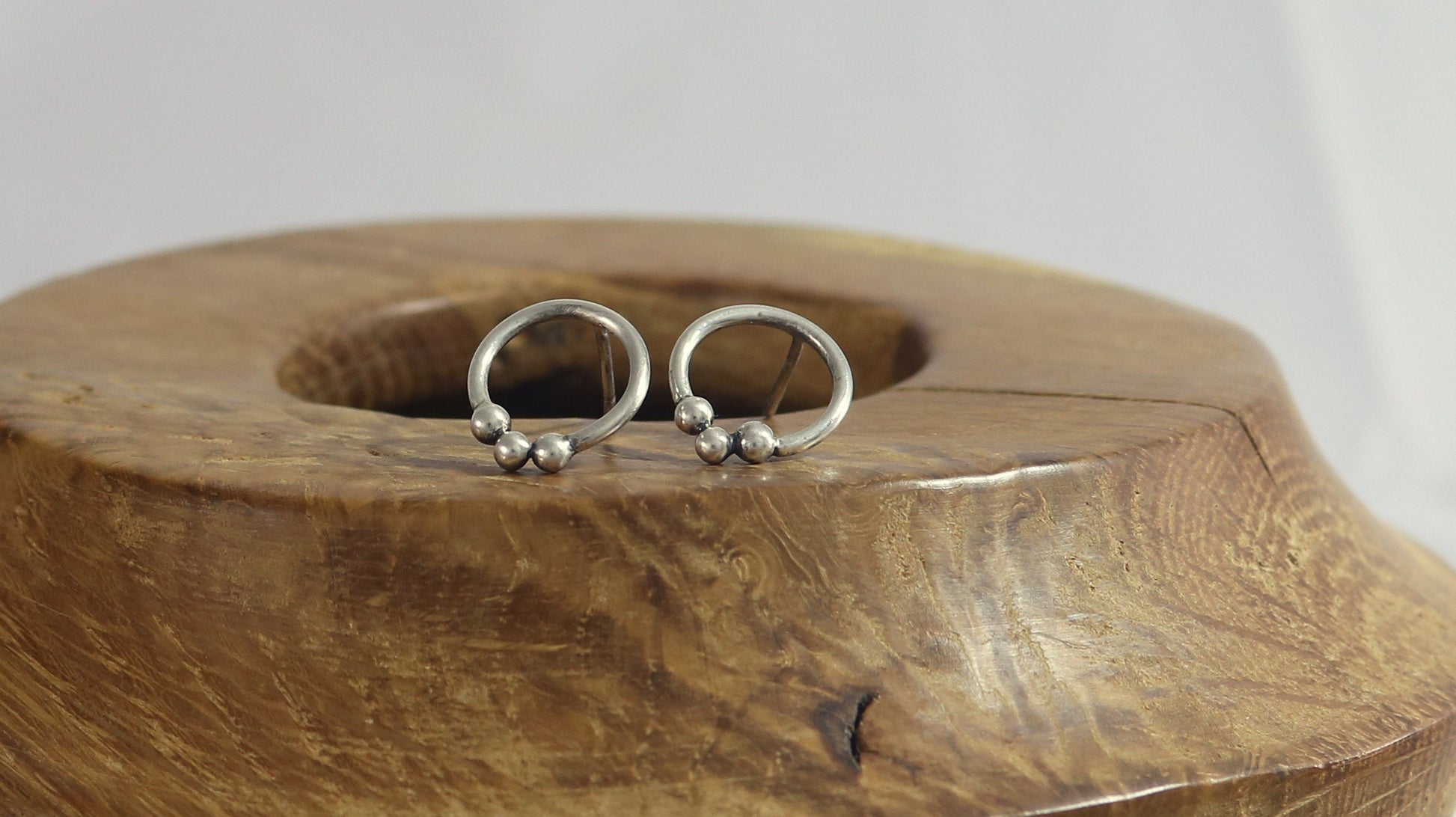 Sterling silver circle stud earrings with three silver bubbles at the bottom.