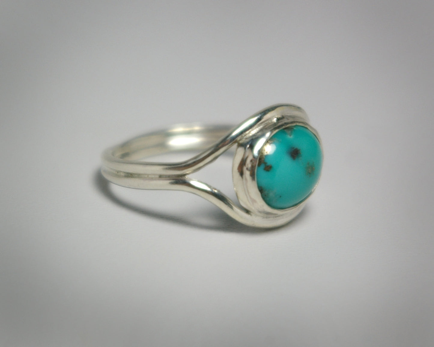 Oval natural gemstone set horizontally in a sterling silver bezel in-between two silver bands that open for the stone.
