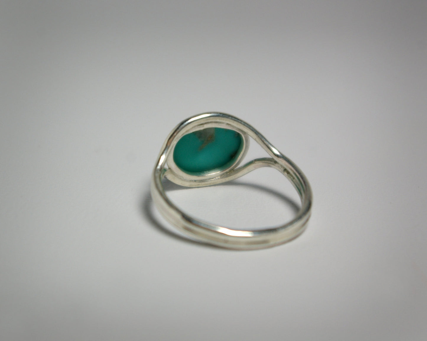 Oval natural gemstone set horizontally in a sterling silver bezel in-between two silver bands that open for the stone.