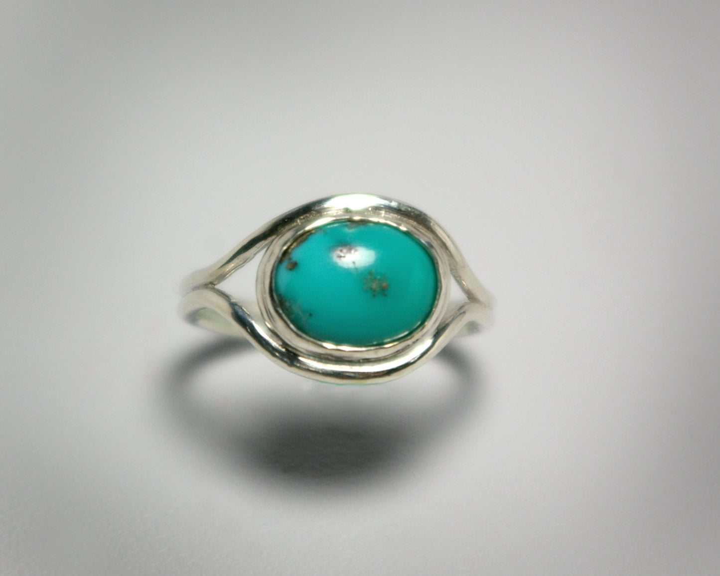 Oval natural gemstone set horizontally in a sterling silver bezel in-between two silver bands that open for the stone.