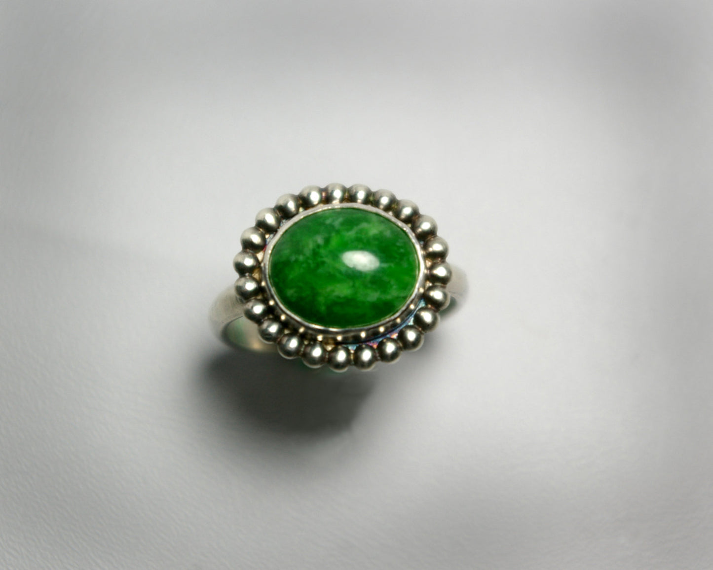Horizontal oval natural gemstone set in sterling silver bezel with halo of silver bubbles.