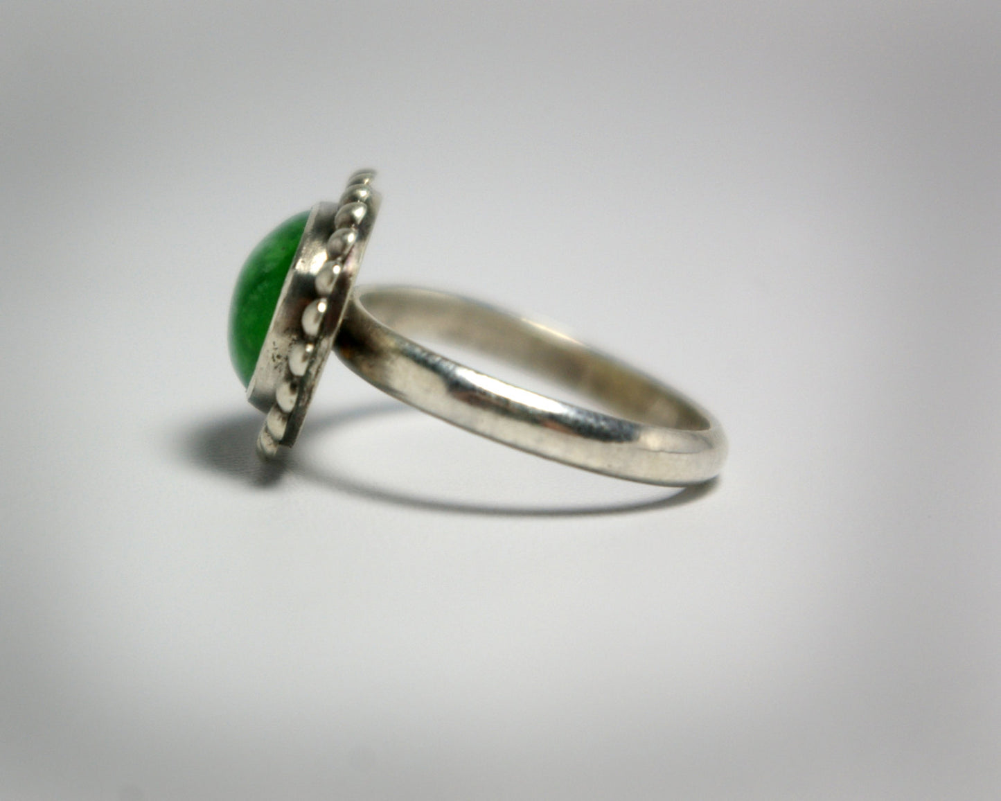Horizontal oval natural gemstone set in sterling silver bezel with halo of silver bubbles.