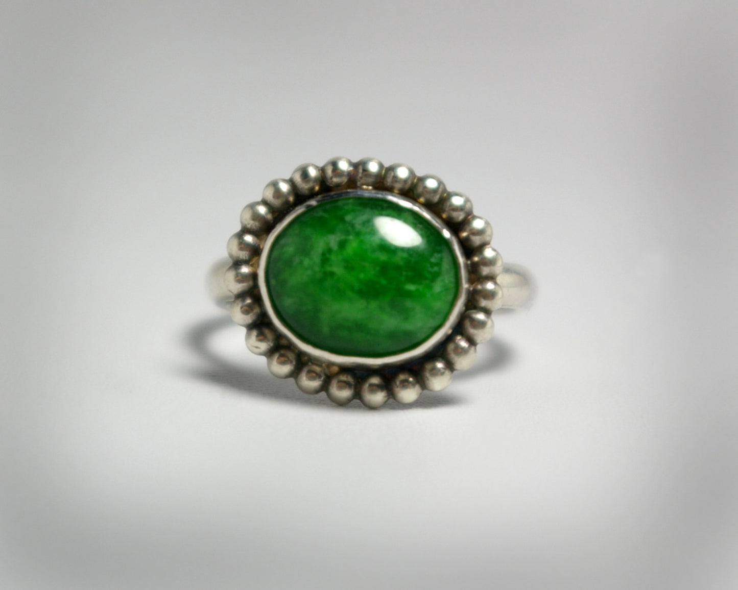 Horizontal oval natural gemstone set in sterling silver bezel with halo of silver bubbles.