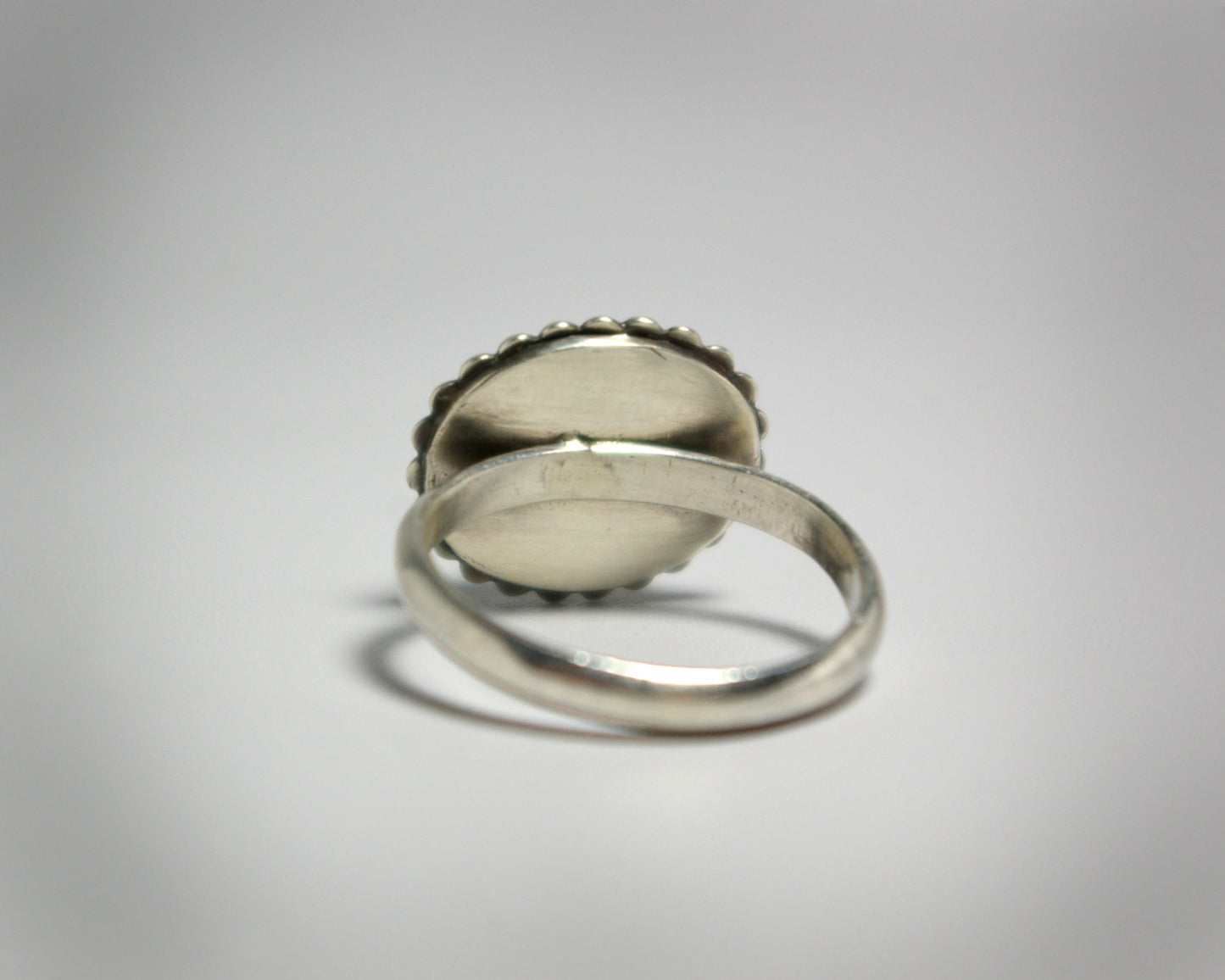 Horizontal oval natural gemstone set in sterling silver bezel with halo of silver bubbles.