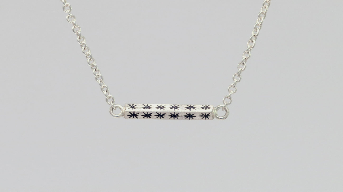 Sterling silver bar necklace with hand cut black stars on every side on a sterling silver chain.
