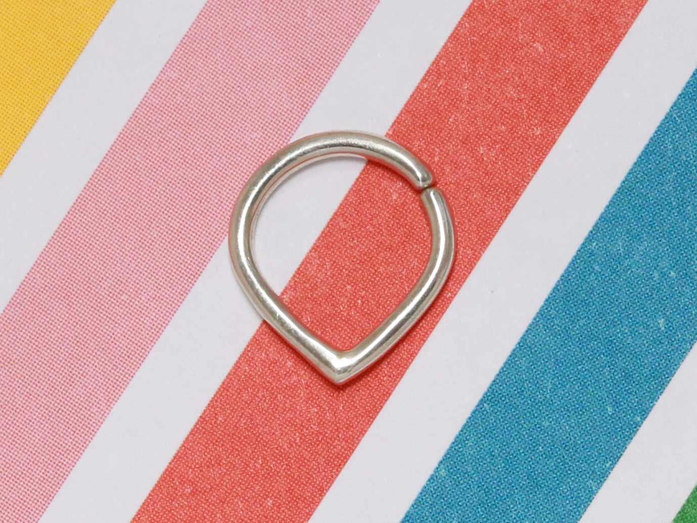 A sterling silver hoop with an opening at the top and a pointed base. To be worn as body jewelry 