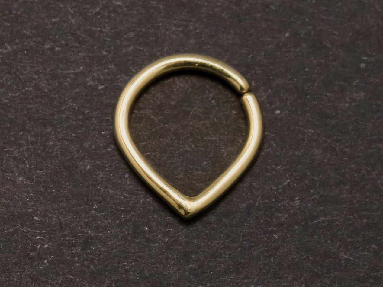 A yellow gold hoop with an opening at the top and a pointed base. To be worn as body jewelry