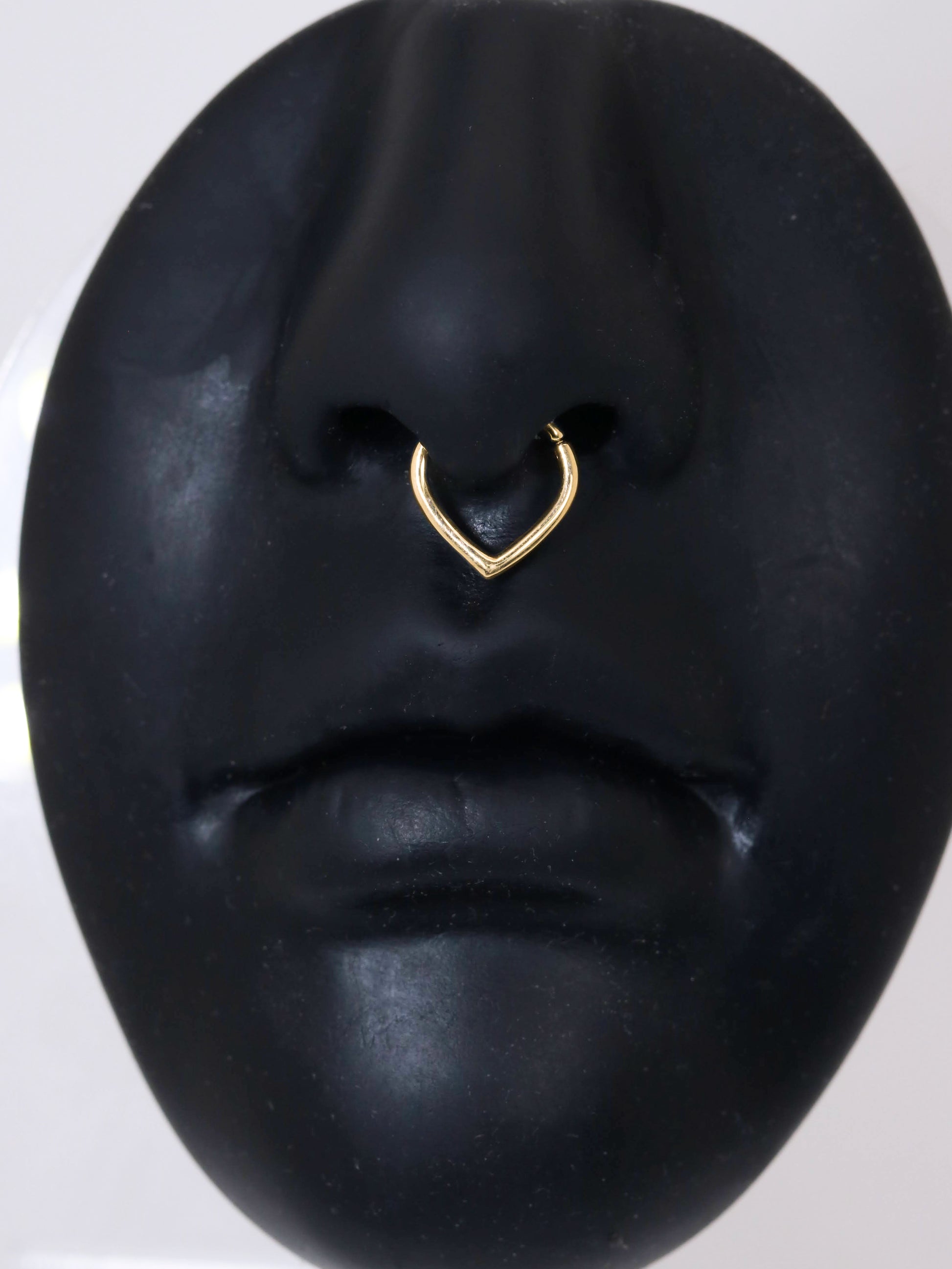 A yellow gold hoop with an opening at the top and a pointed base. To be worn as body jewelry