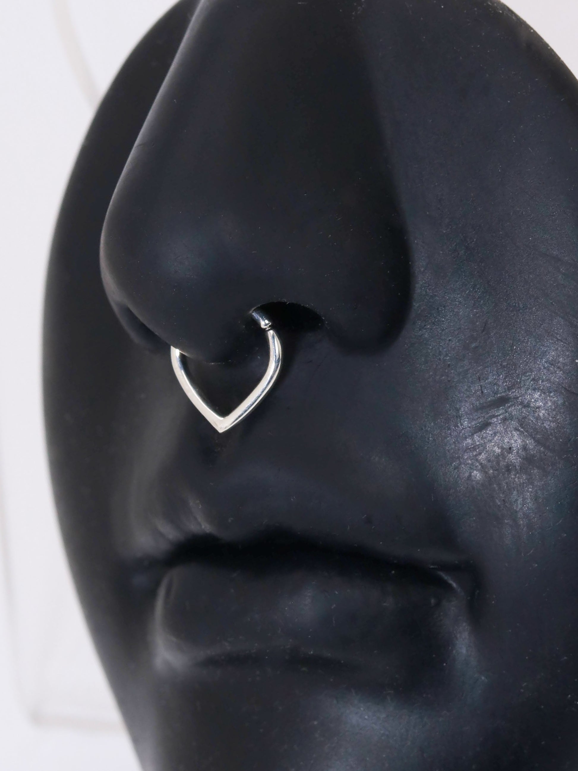 A sterling silver hoop with an opening at the top and a pointed base. To be worn as body jewelry