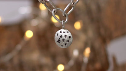 Handmade out of sterling silver, this oval chain link bracelet features a handmade sterling silver charm with hand carved stars.