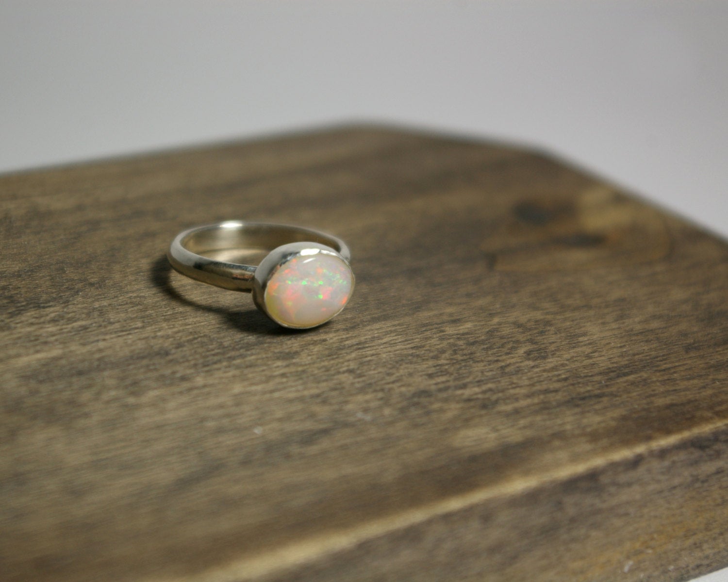 Oval natural white opal set in sterling silver bezel on a sterling silver ring band.