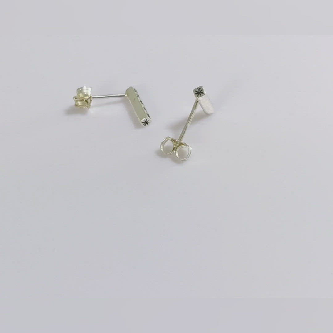 Sterling silver bar stud earrings with hand cut black stars.