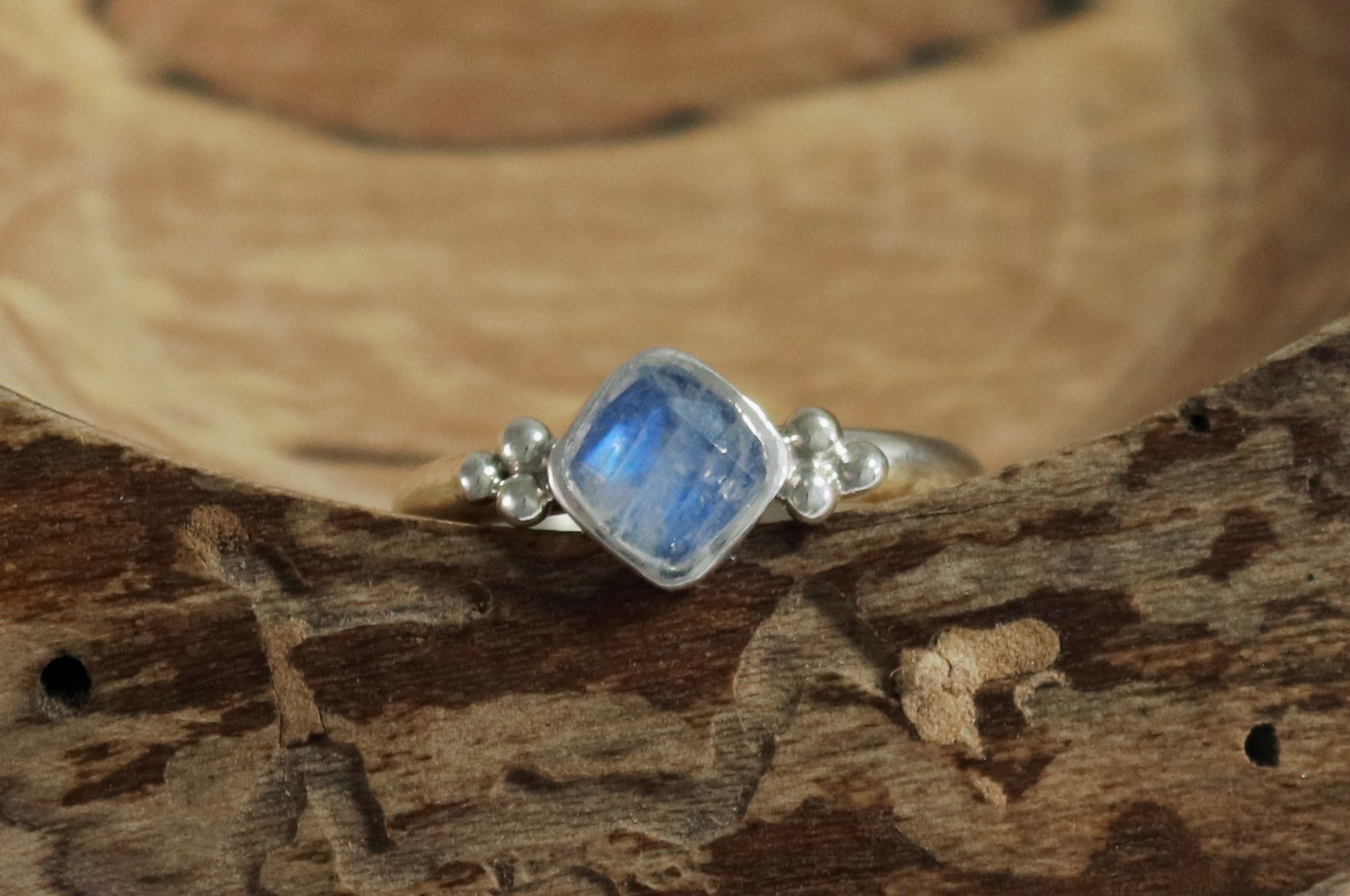 Natural cushion cut rainbow moonstone set in sterling silver with 2 silver bubble pyramid accents on a sterling silver ring band.