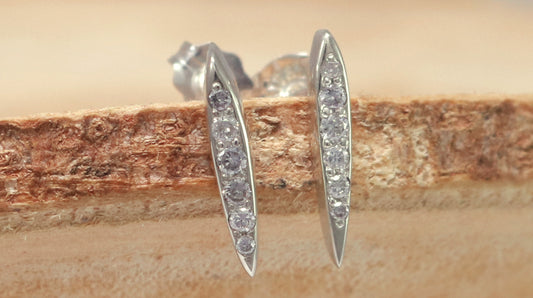 Studs made from solid sterling silver, shaped like a pointed ellipse, bead set with 6 diamonds descending in size.