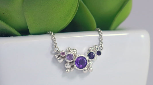 Different shades of round amethyst stones, surrounded by silver bubbles on a silver chain.