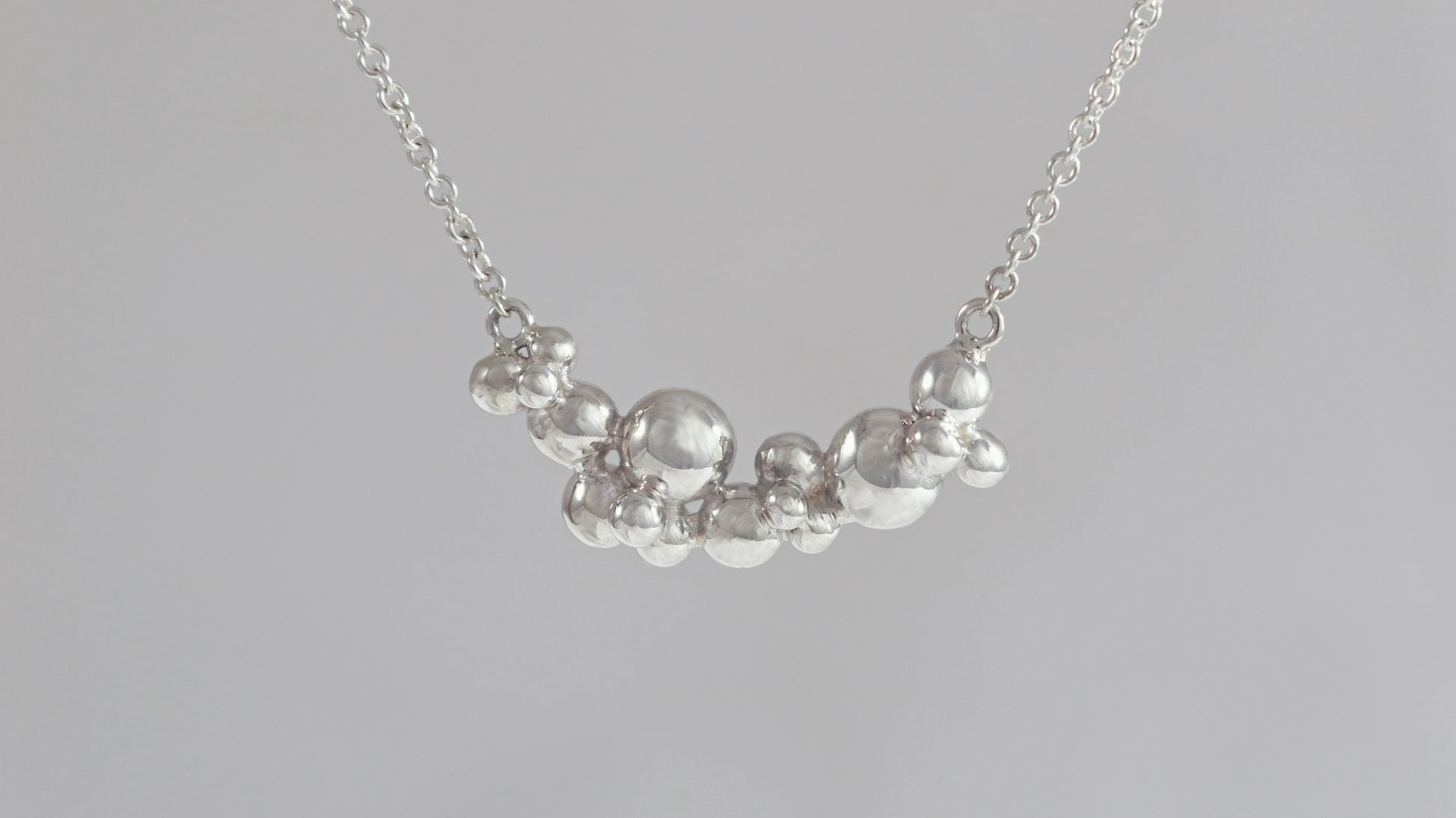 A curved cluster of silver bubbles of different sizes on a sterling silver chain.