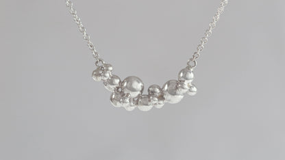 A curved cluster of silver bubbles of different sizes on a sterling silver chain.