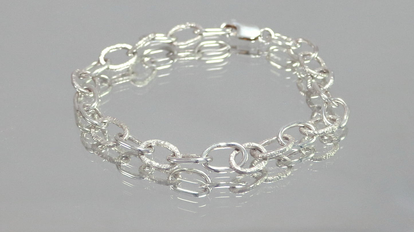 A solid sterling silver oval chain link bracelet mixed polished and textured links.