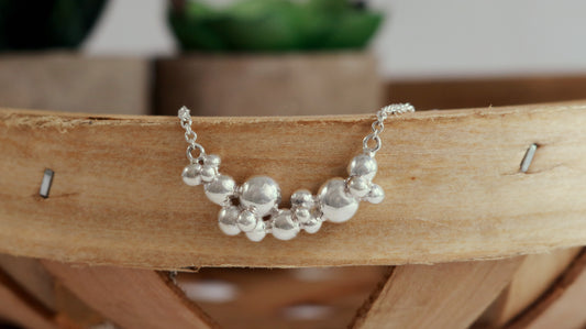 A curved cluster of silver bubbles of different sizes on a sterling silver chain.
