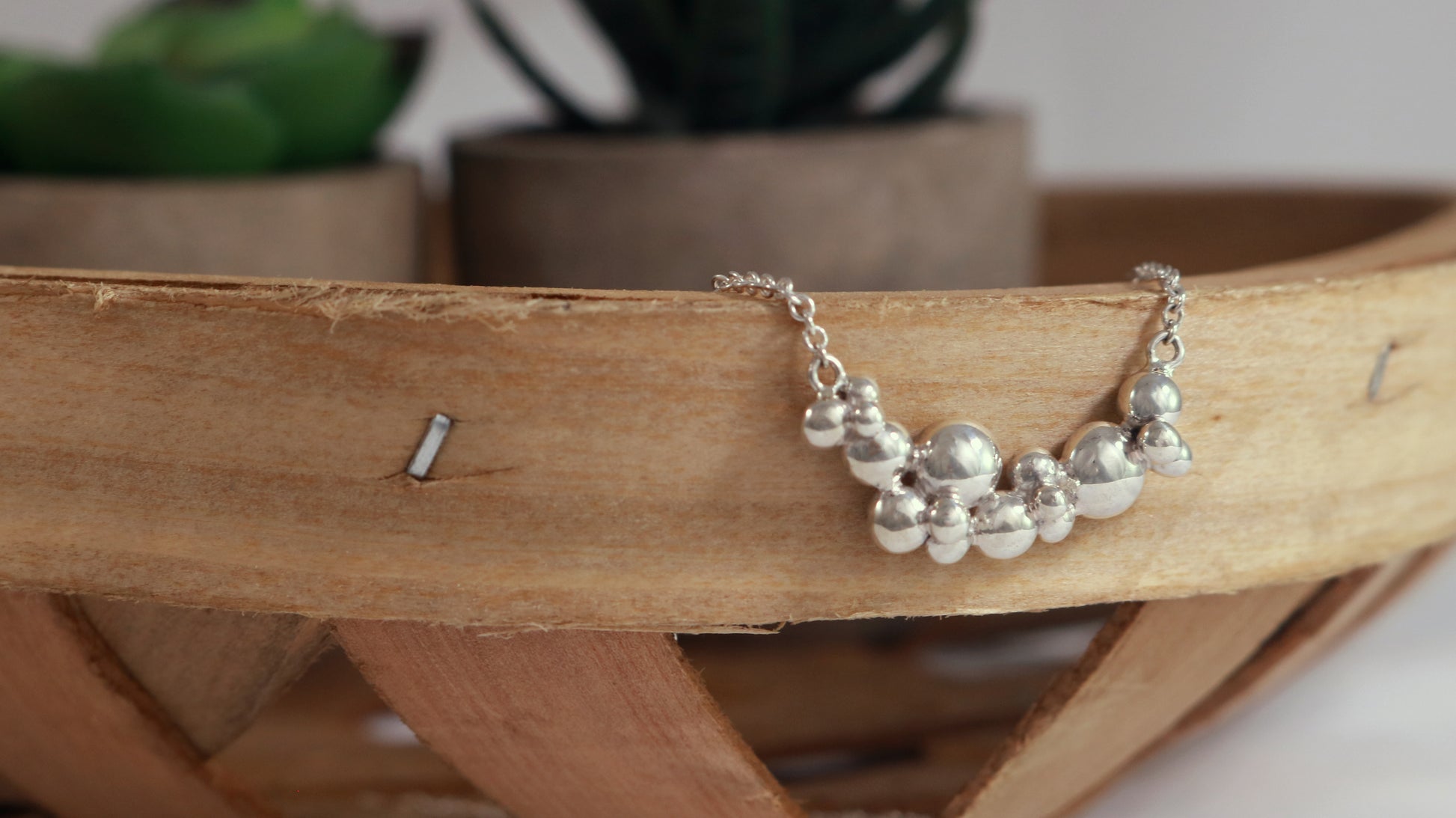 A curved cluster of silver bubbles of different sizes on a sterling silver chain.