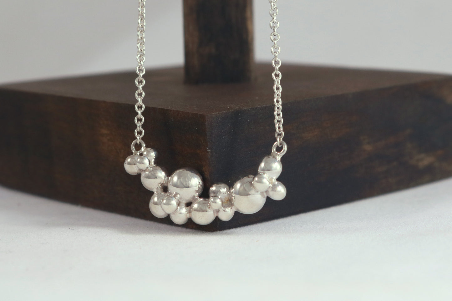 A curved cluster of silver bubbles of different sizes on a sterling silver chain.