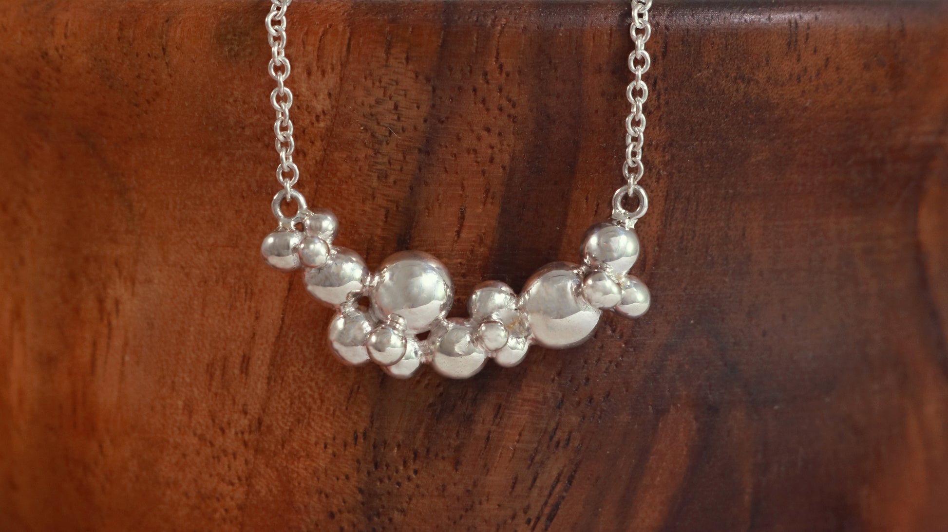 A curved cluster of silver bubbles of different sizes on a sterling silver chain.