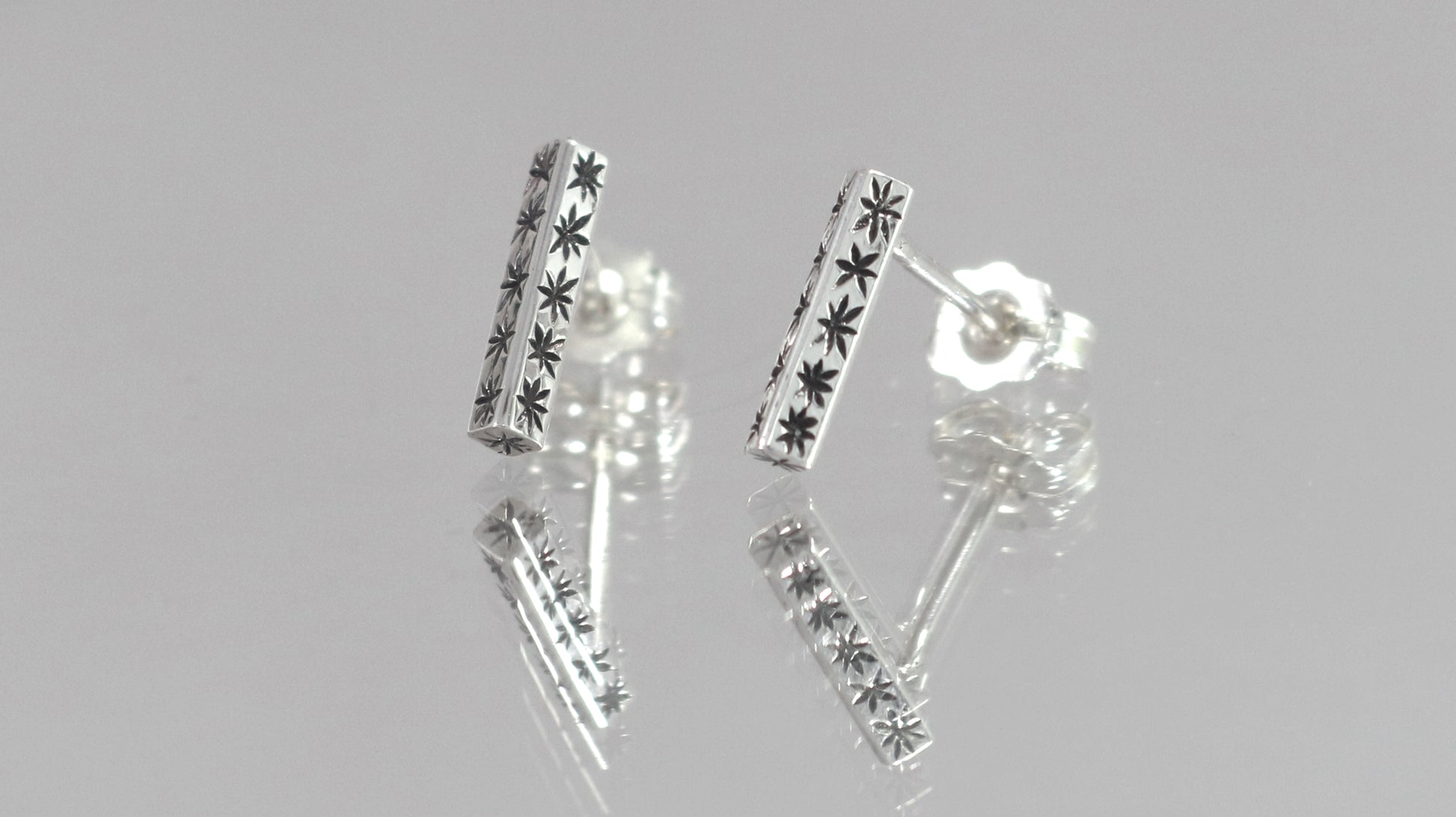 Sterling silver bar stud earrings with hand cut black stars.